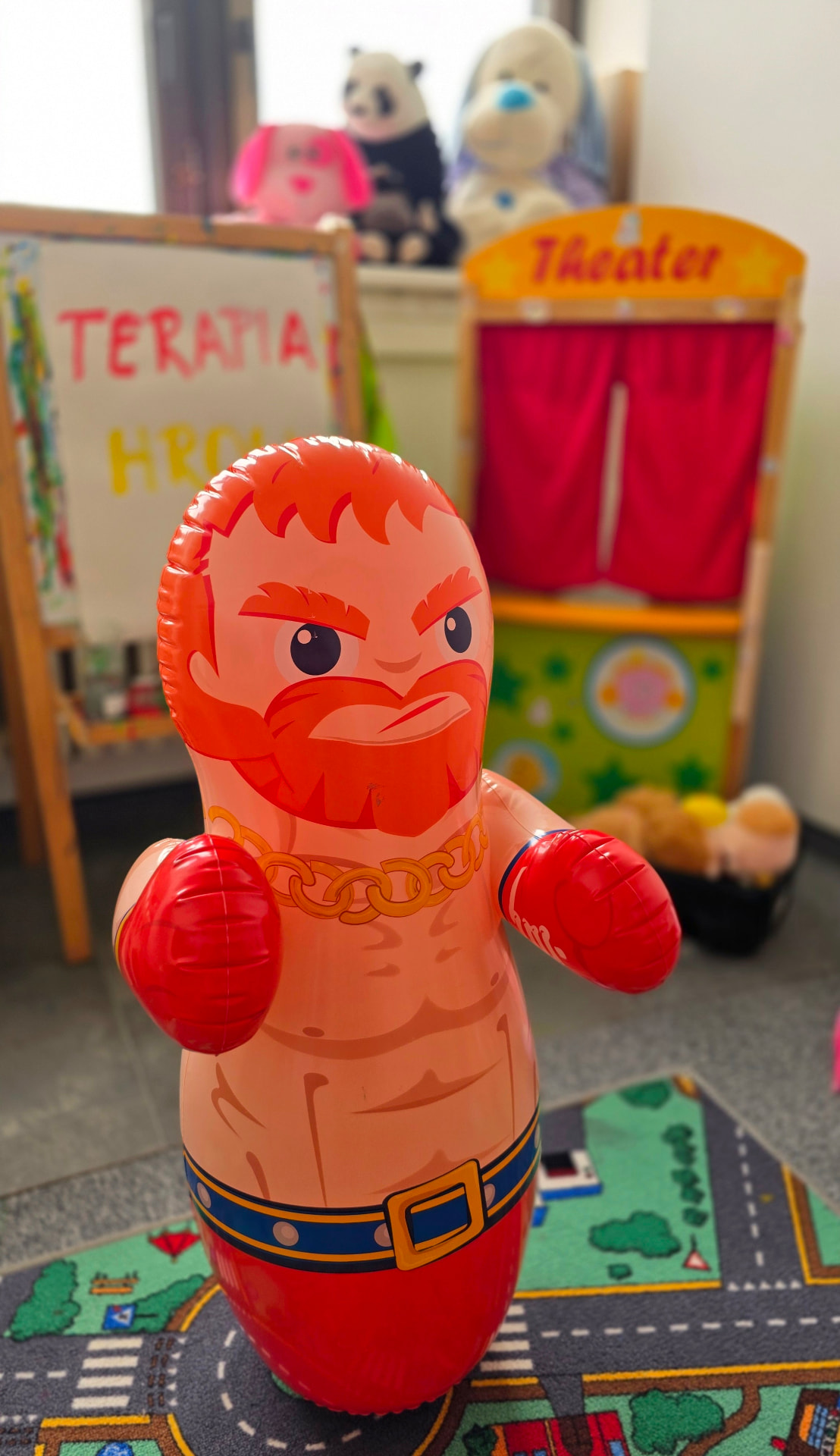 Nafukovací panák s červenými boxerskými rukavicami stojaci na koberci s cestami